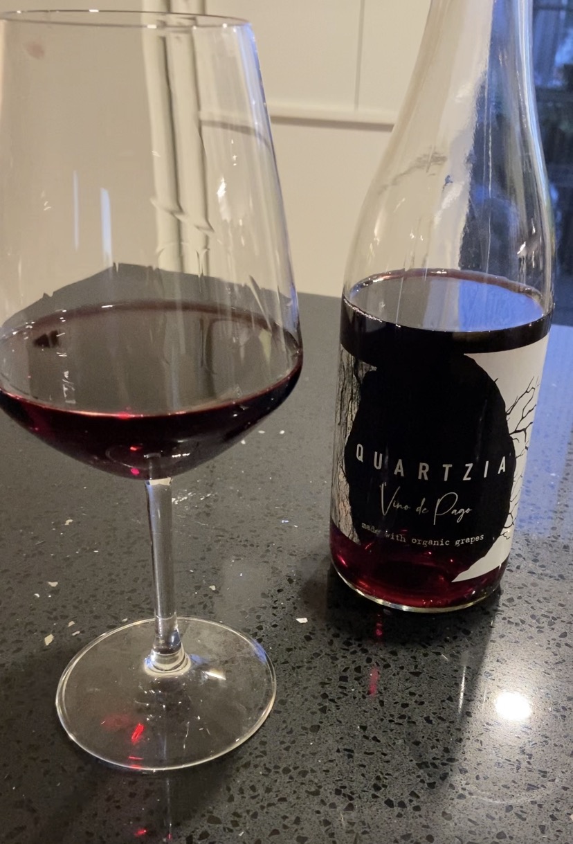 A glass of Quartzia Garnacha poured beside the bottle, its label reading Vino de Pago, made with organic grapes